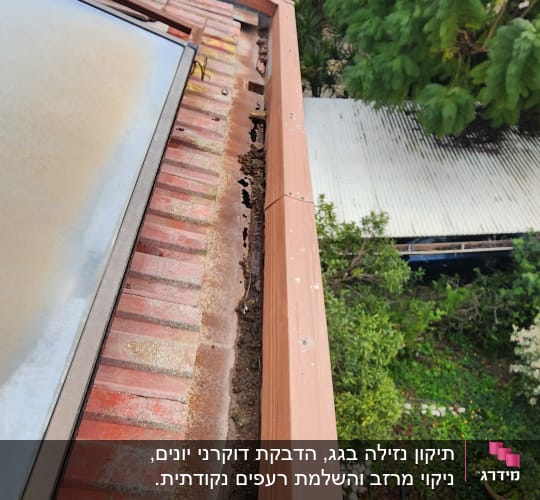 רעפים אדומים על גג עם חלודה ונזק לאורך הקצה